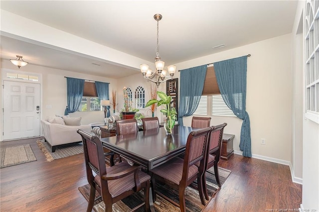 dining space featuring dark wood-style floors, a wealth of natural light, and an inviting chandelier