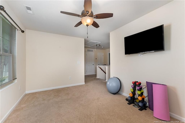 exercise room with visible vents, carpet, baseboards, attic access, and ceiling fan