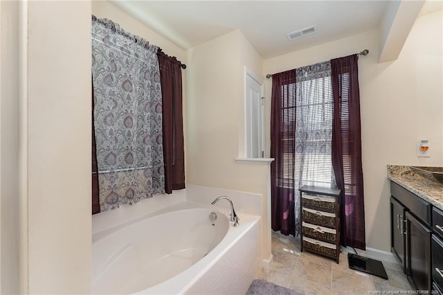 bathroom featuring tiled tub, vanity, and tile patterned flooring