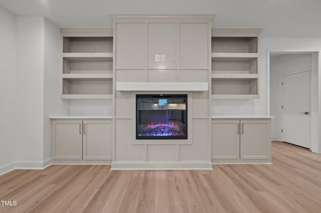 unfurnished living room with light wood-type flooring and built in shelves