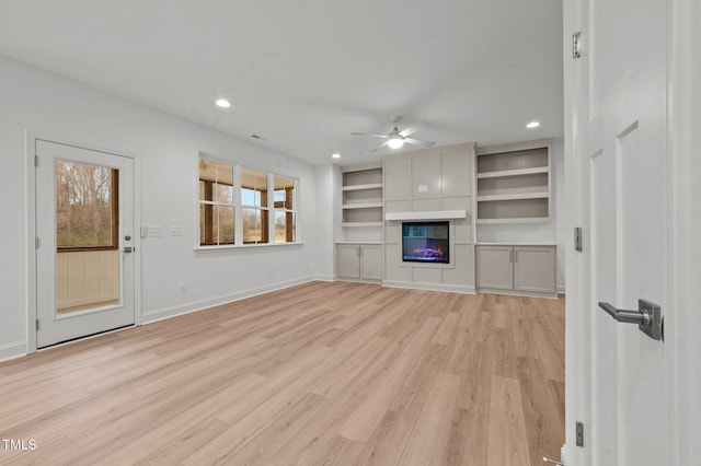 unfurnished living room with ceiling fan, a fireplace, and light wood-type flooring