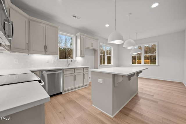 kitchen featuring pendant lighting, dishwasher, backsplash, a center island, and light hardwood / wood-style floors