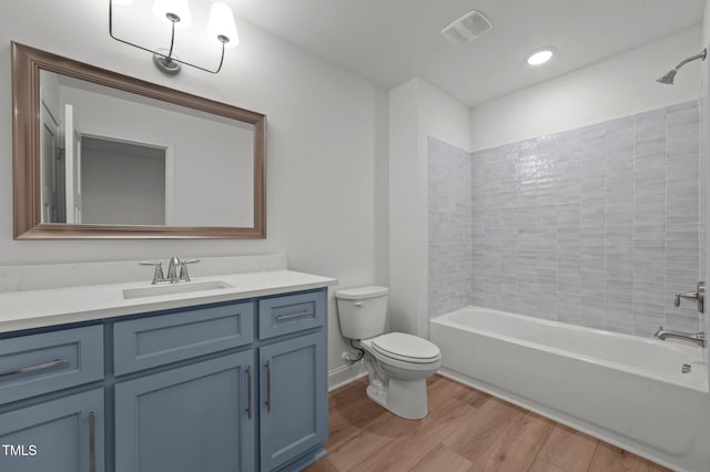 full bathroom featuring vanity, hardwood / wood-style floors, toilet, and tiled shower / bath