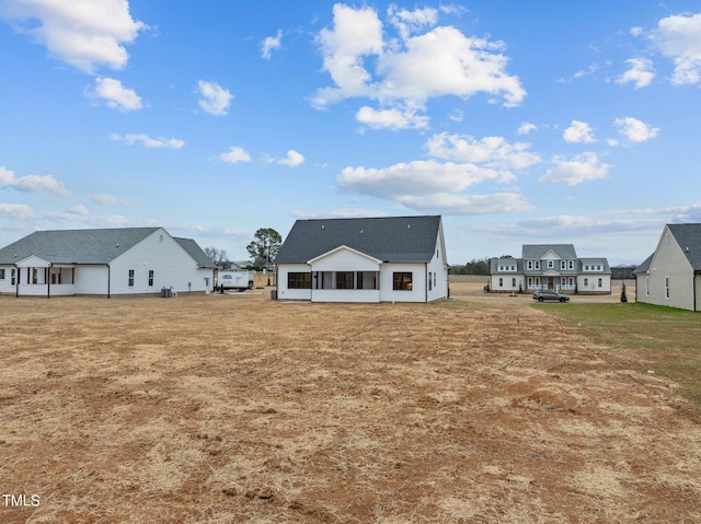 rear view of house featuring a sunroom and a lawn