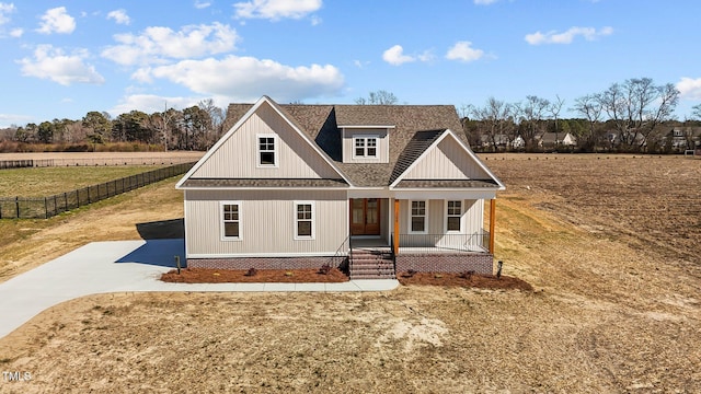 view of front of property with a shingled roof, covered porch, fence, and concrete driveway