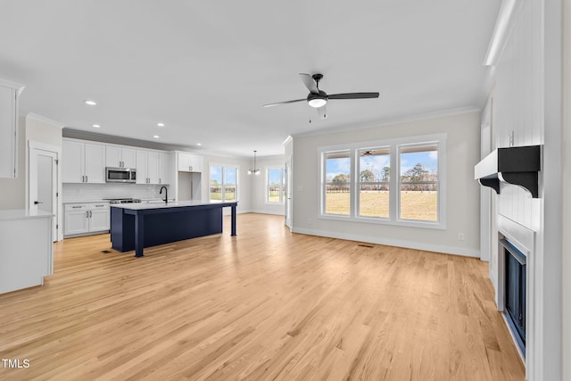 living room with light wood finished floors, a large fireplace, ornamental molding, and baseboards