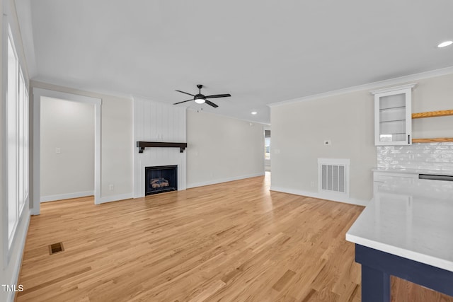 unfurnished living room with a large fireplace, visible vents, and crown molding