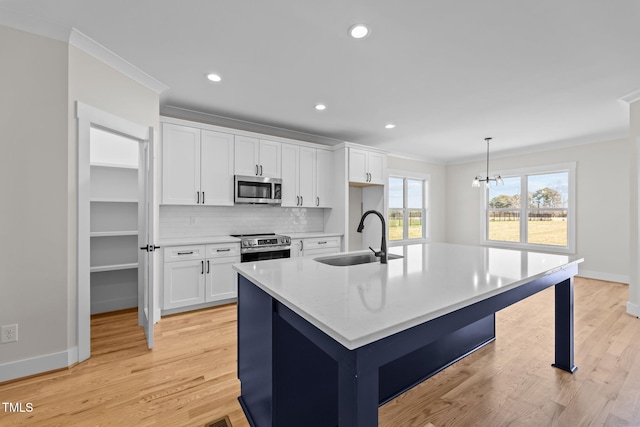 kitchen with stainless steel appliances, a sink, white cabinets, and crown molding