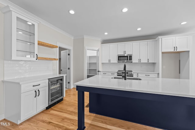 kitchen with beverage cooler, stainless steel microwave, light countertops, and a sink