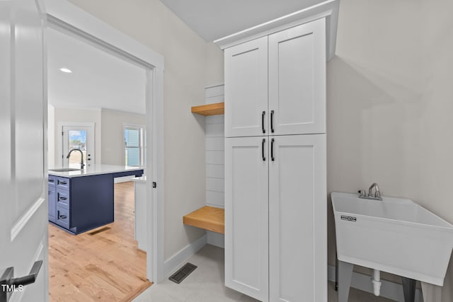 mudroom with visible vents, a sink, light wood-style flooring, and baseboards