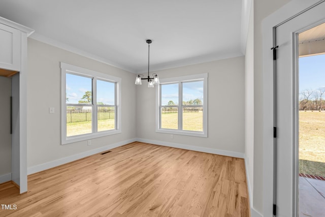 unfurnished dining area featuring visible vents, an inviting chandelier, light wood-style floors, ornamental molding, and baseboards