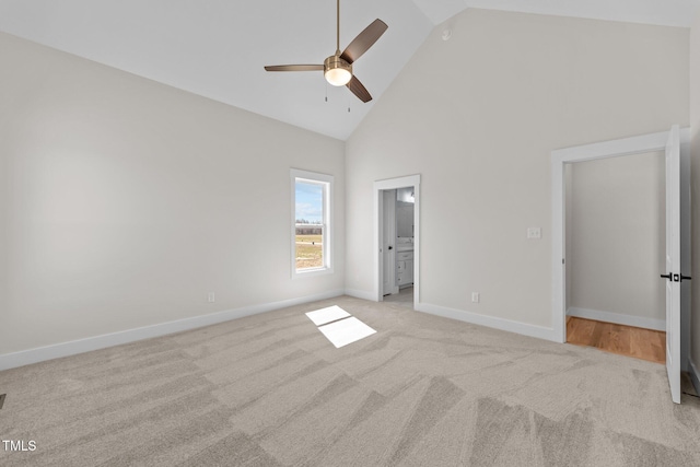 unfurnished bedroom featuring carpet, baseboards, high vaulted ceiling, and ensuite bathroom