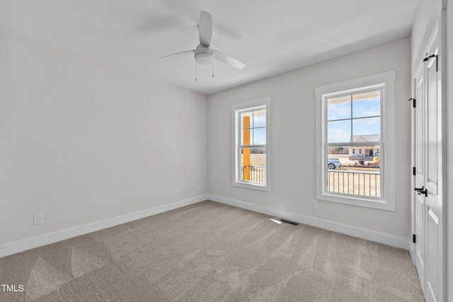 carpeted empty room with ceiling fan, visible vents, and baseboards