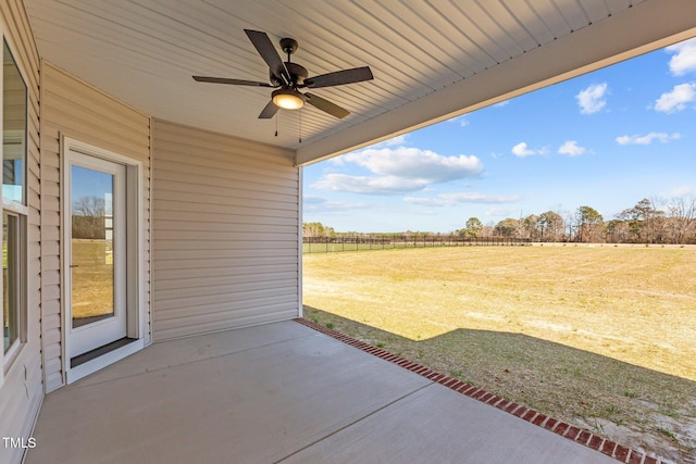 view of patio with ceiling fan, a rural view, and fence