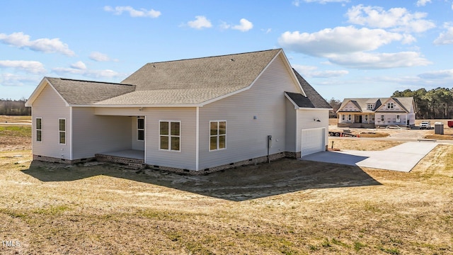 rear view of house featuring roof with shingles, crawl space, a patio area, and driveway