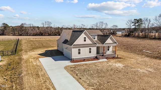 view of front of property featuring covered porch, concrete driveway, roof with shingles, and fence