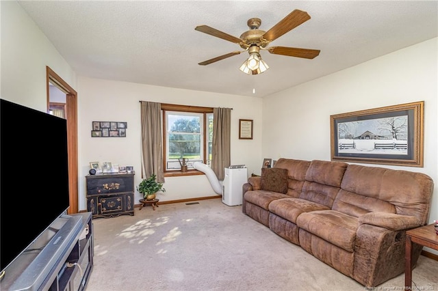 living room with ceiling fan, light colored carpet, and a textured ceiling