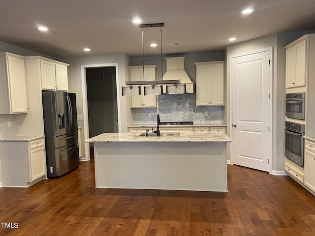 kitchen with stainless steel appliances, dark hardwood / wood-style floors, and a kitchen island with sink