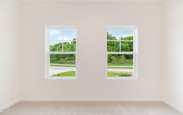 spare room featuring light colored carpet and baseboards