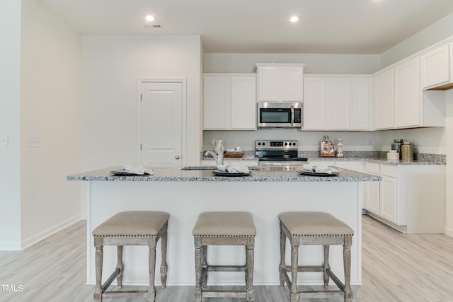 kitchen featuring a kitchen island with sink, appliances with stainless steel finishes, and white cabinets