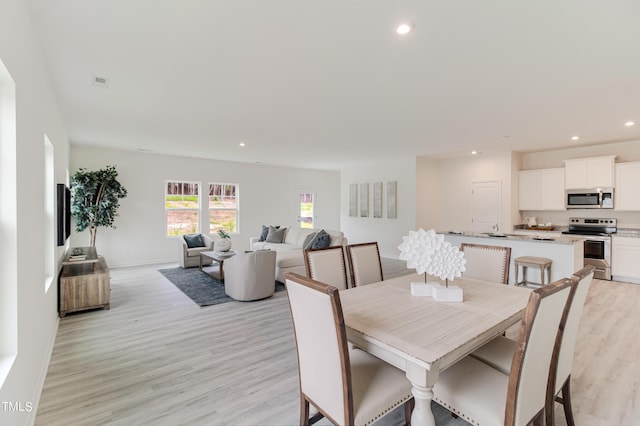 dining area with baseboards, light wood-type flooring, and recessed lighting