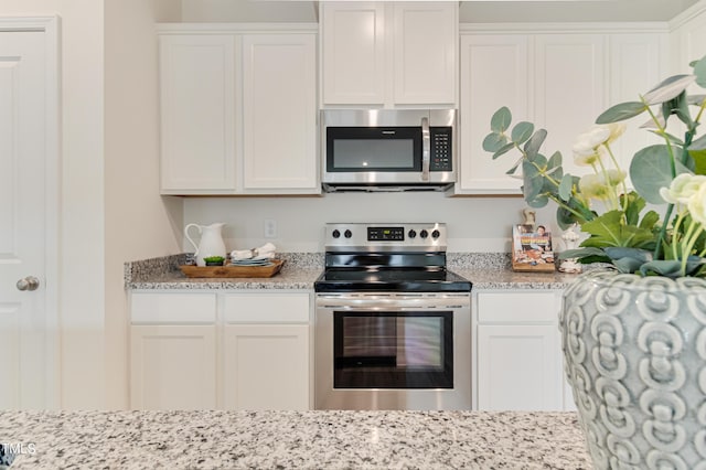 kitchen featuring stainless steel appliances, white cabinetry, and light stone counters