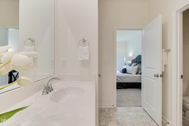 ensuite bathroom with marble finish floor, toilet, connected bathroom, a sink, and baseboards