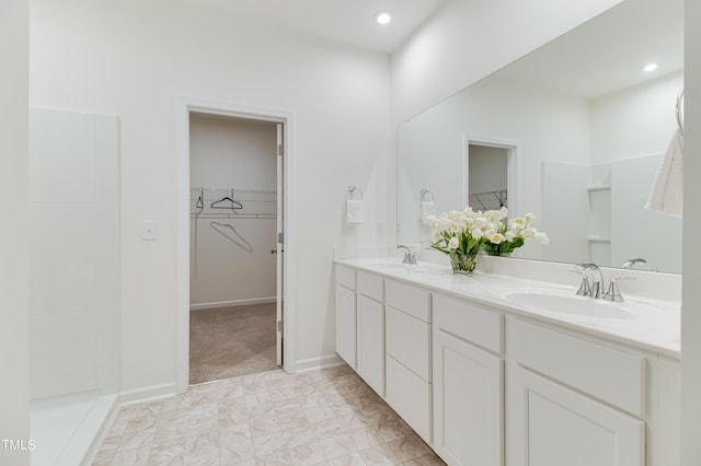 full bath featuring double vanity, a spacious closet, a sink, and recessed lighting