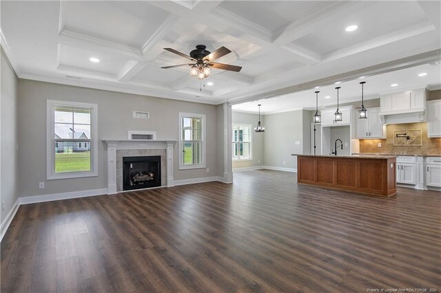 unfurnished living room with coffered ceiling, beamed ceiling, a fireplace, dark wood-type flooring, and ceiling fan