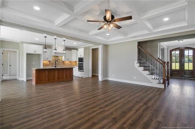 unfurnished living room featuring coffered ceiling, beam ceiling, ceiling fan, and dark hardwood / wood-style floors