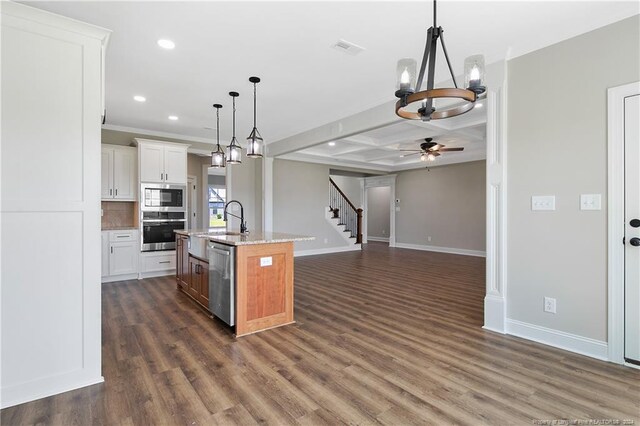 kitchen featuring ceiling fan with notable chandelier, stainless steel appliances, dark hardwood / wood-style flooring, coffered ceiling, and a center island with sink