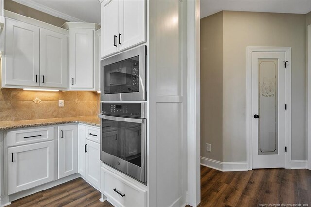 kitchen featuring built in microwave, oven, white cabinets, and dark wood-type flooring