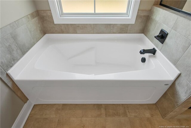 bathroom with tile patterned floors, a bathing tub, and a healthy amount of sunlight