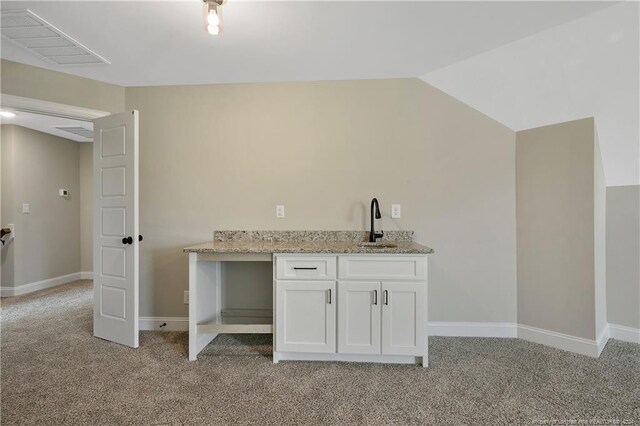 bar with light carpet, lofted ceiling, light stone countertops, and white cabinets