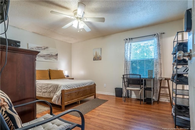 bedroom with a textured ceiling, ceiling fan, and wood-type flooring