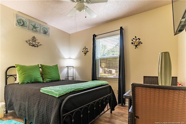 bedroom featuring ceiling fan, hardwood / wood-style flooring, and a textured ceiling