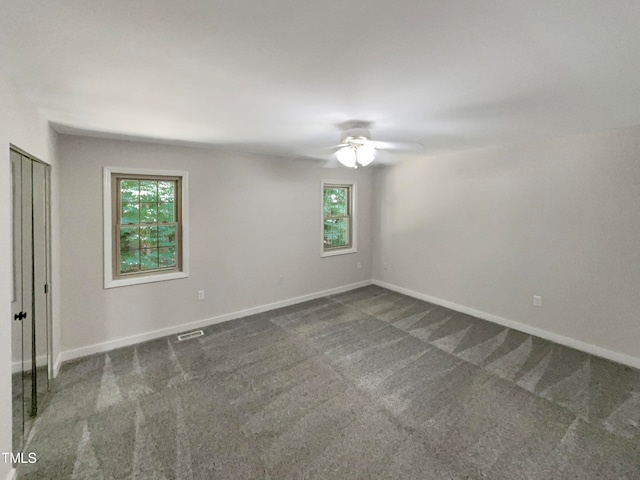 carpeted empty room with a wealth of natural light and ceiling fan