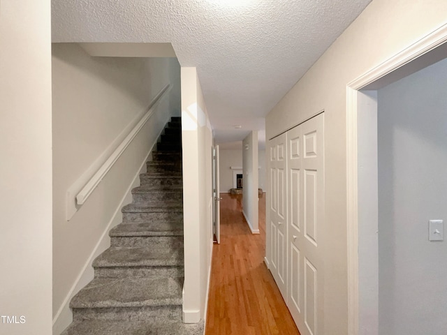 staircase featuring a textured ceiling and hardwood / wood-style flooring