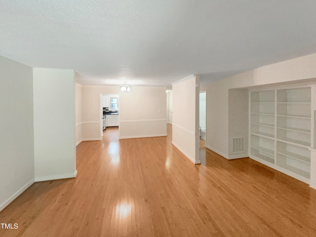 spare room with light wood-type flooring and a textured ceiling