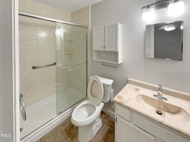 bathroom featuring tile patterned floors, vanity, toilet, and a shower with shower door