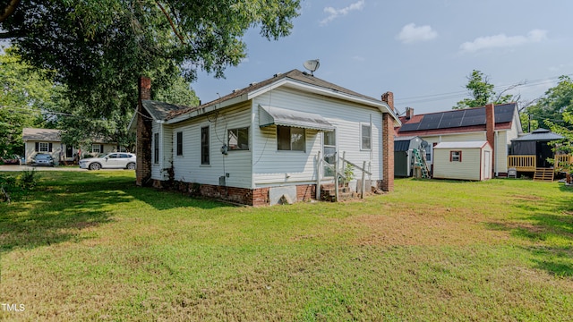 back of house with a storage shed and a yard