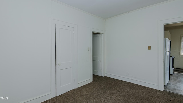 unfurnished bedroom with white fridge, carpet, and crown molding