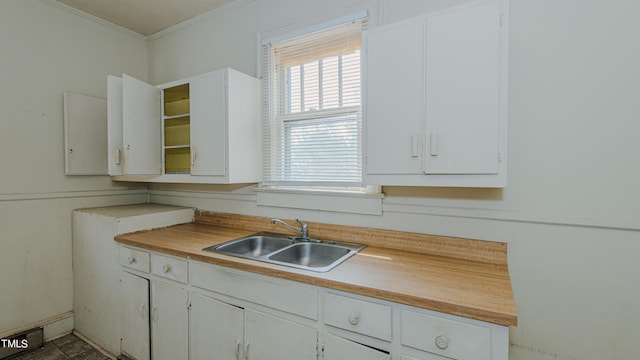 kitchen with crown molding, sink, and white cabinetry