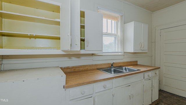 kitchen with crown molding, white cabinetry, and sink