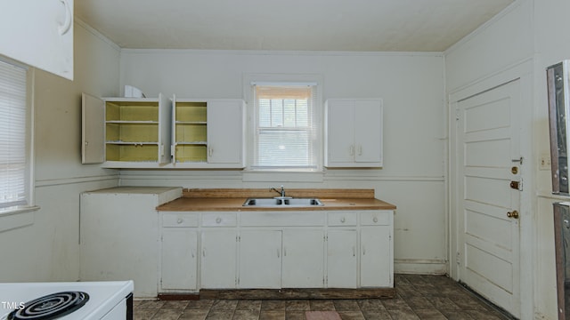 kitchen featuring white stove, sink, and white cabinetry