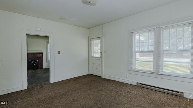 empty room with a fireplace, plenty of natural light, and dark colored carpet