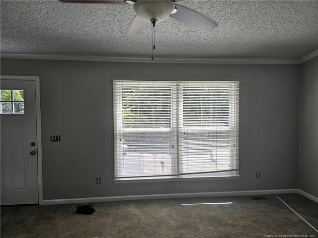 spare room with ornamental molding, ceiling fan, dark colored carpet, and a textured ceiling