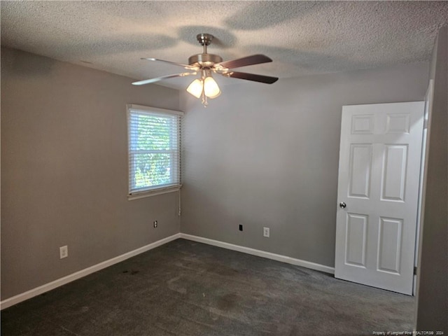 empty room with a textured ceiling, dark colored carpet, and ceiling fan