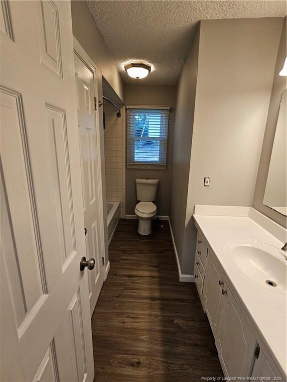 full bathroom featuring toilet, tiled shower / bath, vanity, a textured ceiling, and hardwood / wood-style flooring