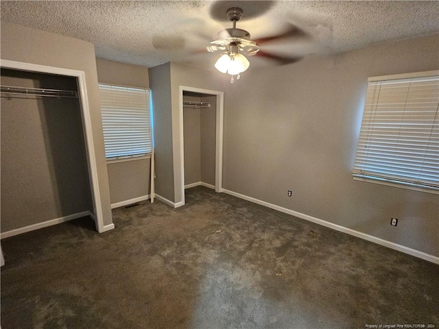 unfurnished bedroom featuring a textured ceiling, dark carpet, and ceiling fan